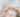 Person in a bath holds out their hands, one in a round hole shape and the other with two fingers pointing to the hole