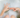 Person in a bath holds out their hands, one in a round hole shape and the other with two fingers pointing to the hole